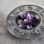 Piatto metallico con simboli zodiacali in rilievo e decorazione di cristalli viola.