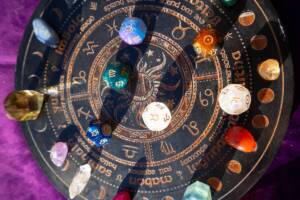 Tavola decorativa con i simboli dei segni zodiacali e cristalli colorati.
