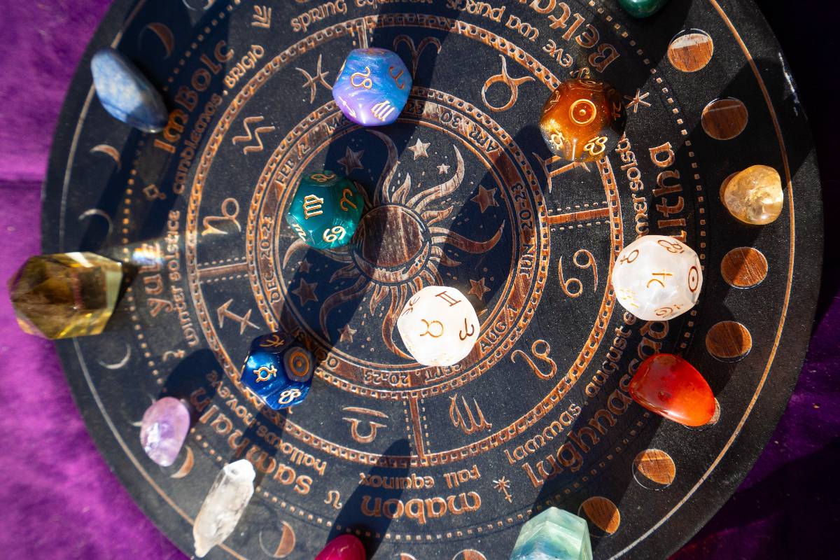Tavola decorativa con i simboli dei segni zodiacali e cristalli colorati.