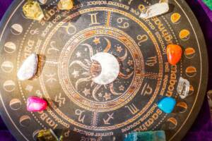 Tavola decorativa con i simboli dei segni zodiacali e cristalli colorati.