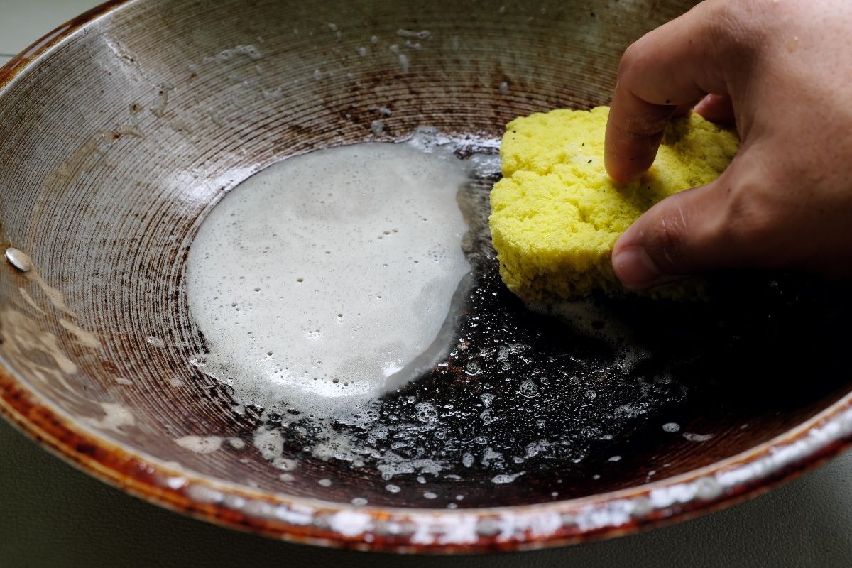 La pulizia di una padella bruciata con la spugna gialla