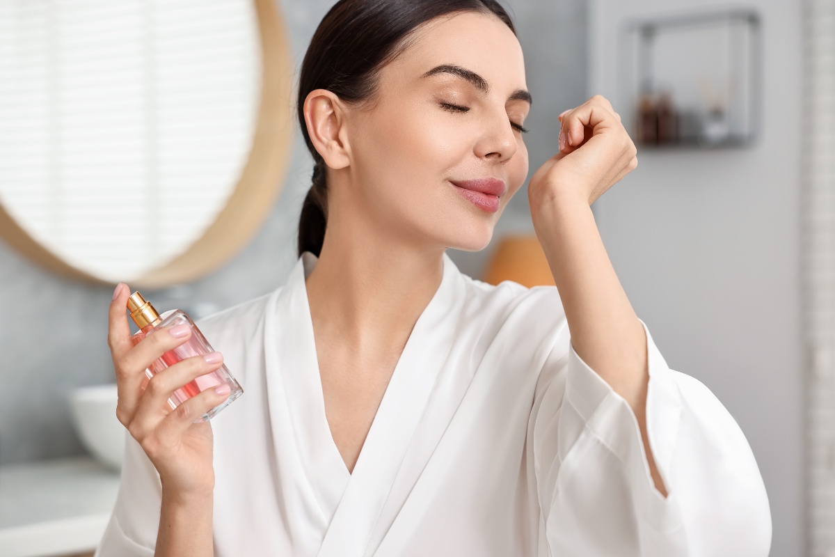 Ragazza davanti allo specchio del bagno mentre indossa il profumo.