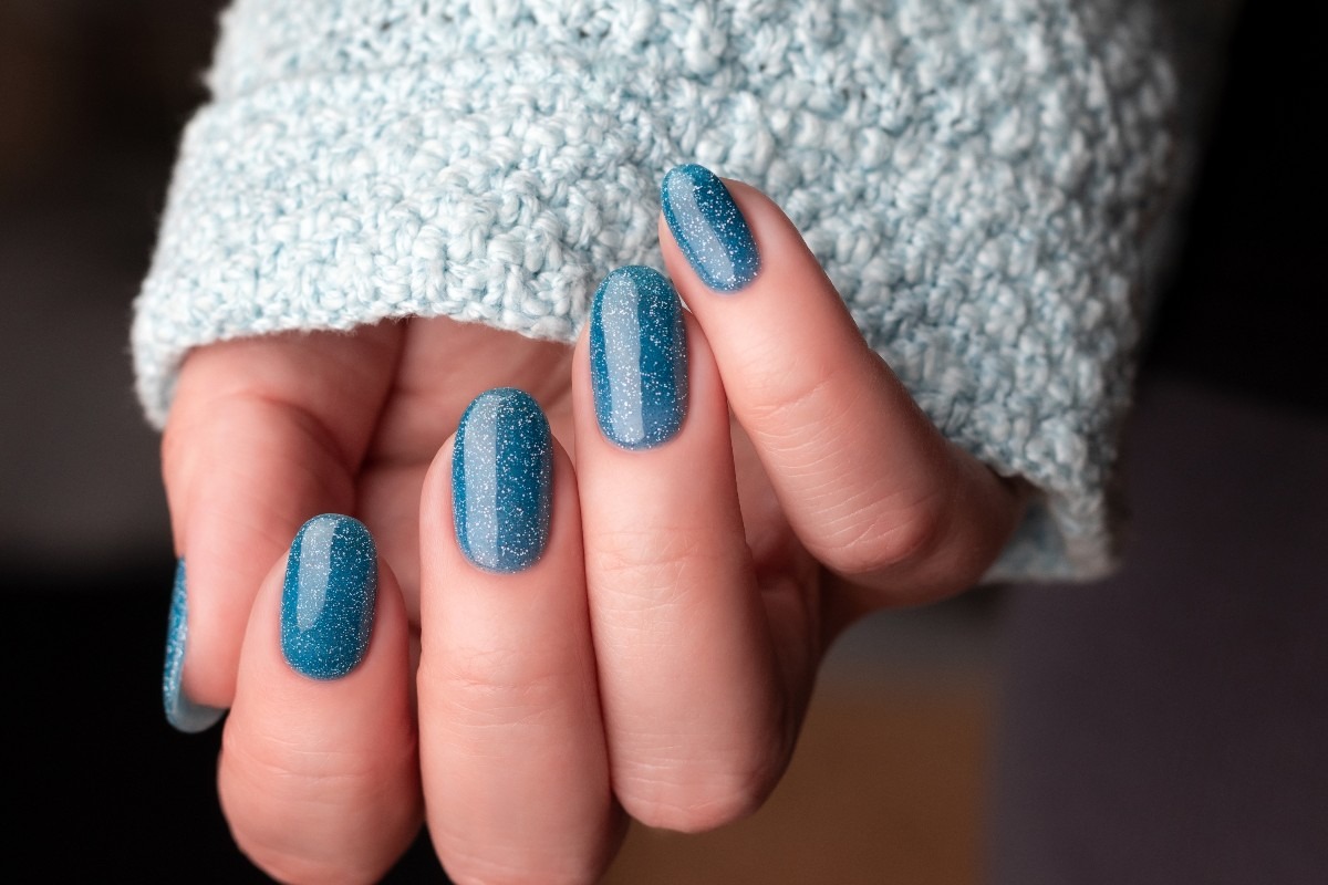 Smalto azzurro con brillantini su mano di donna