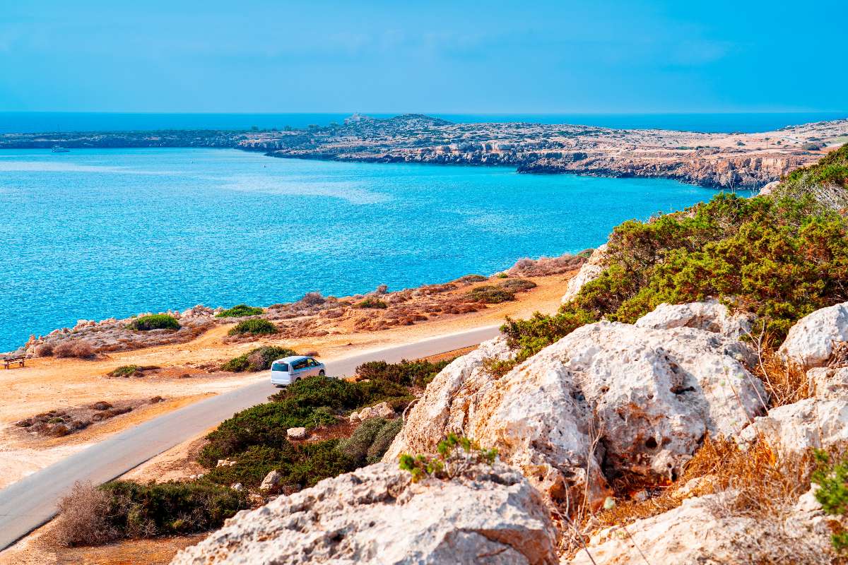 Una strada costiera a Cipro con auto e vista mare.
