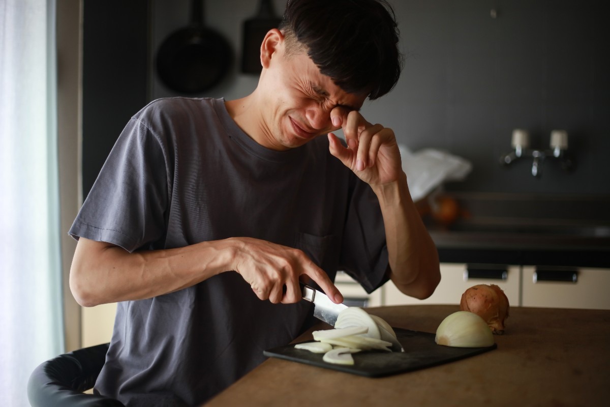 Un uomo piange mentre taglia le cipolle