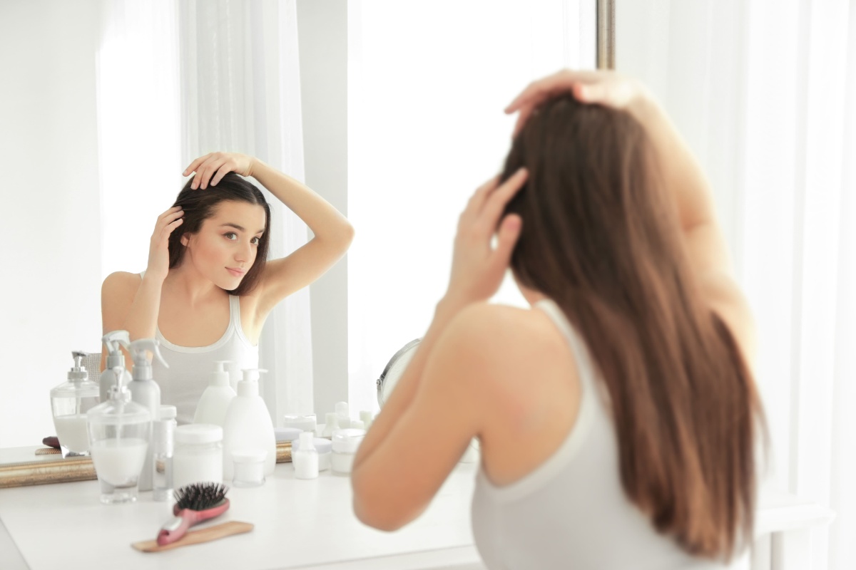 Una ragazza si guarda allo specchio mentre esamina i propri capelli.