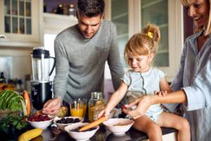 Una famiglia in cucina circondata da frutta e verdura fresca.