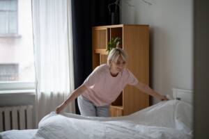 Donna fa il letto con le lenzuola