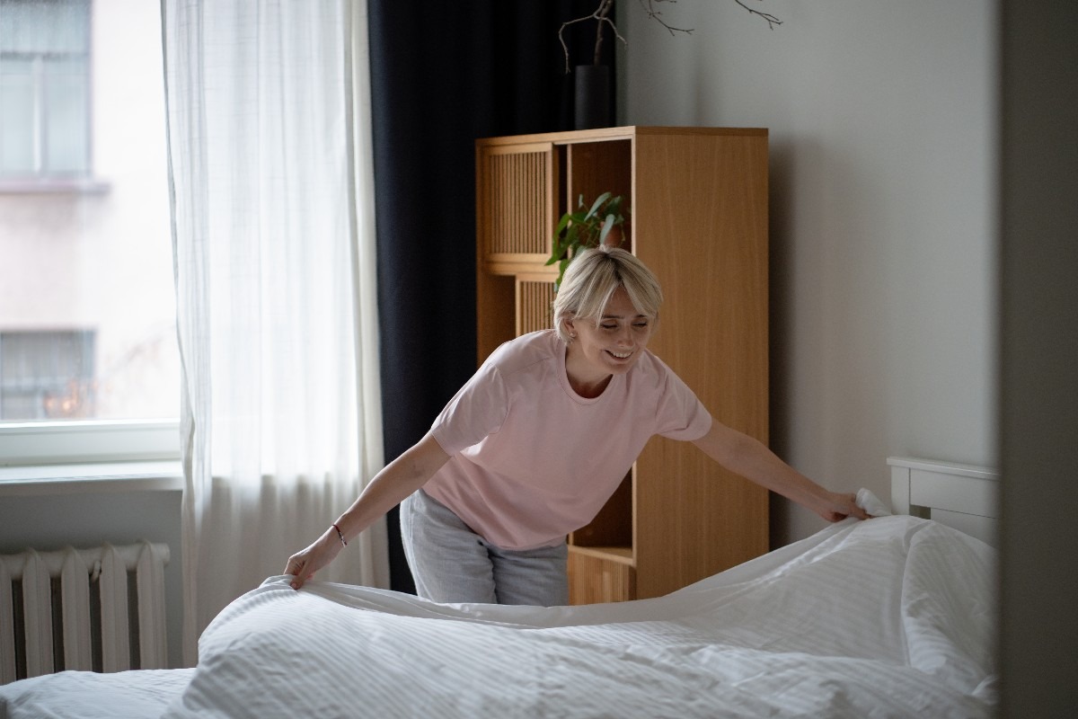 Donna fa il letto con le lenzuola