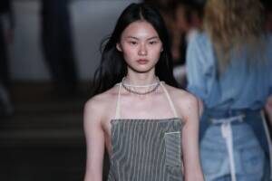 Una modella sfila in passerella con un grembiule rivisitato come accessorio di alta moda.