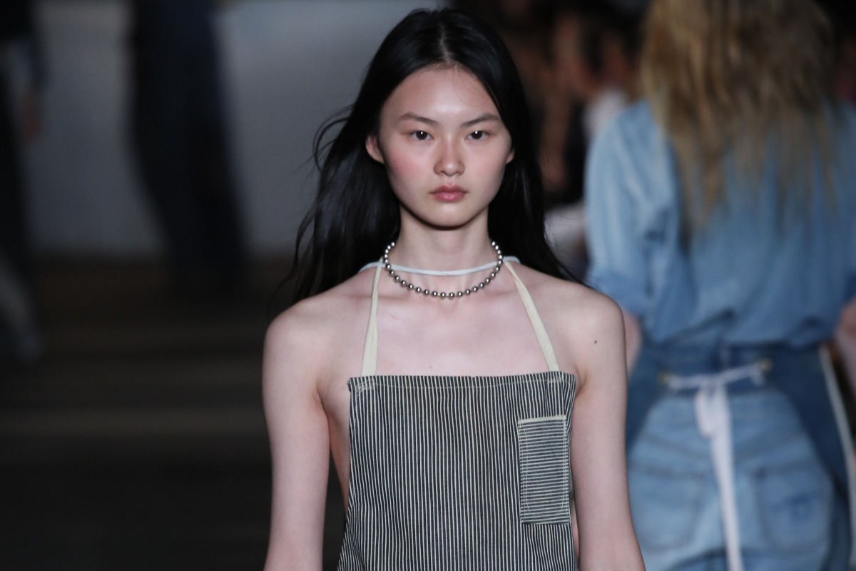 Una modella sfila in passerella con un grembiule rivisitato come accessorio di alta moda.