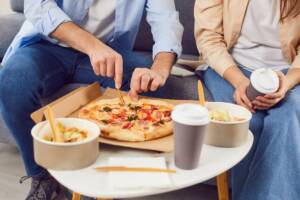 Pizza e altro cibo da asporto consumati su un tavolino.