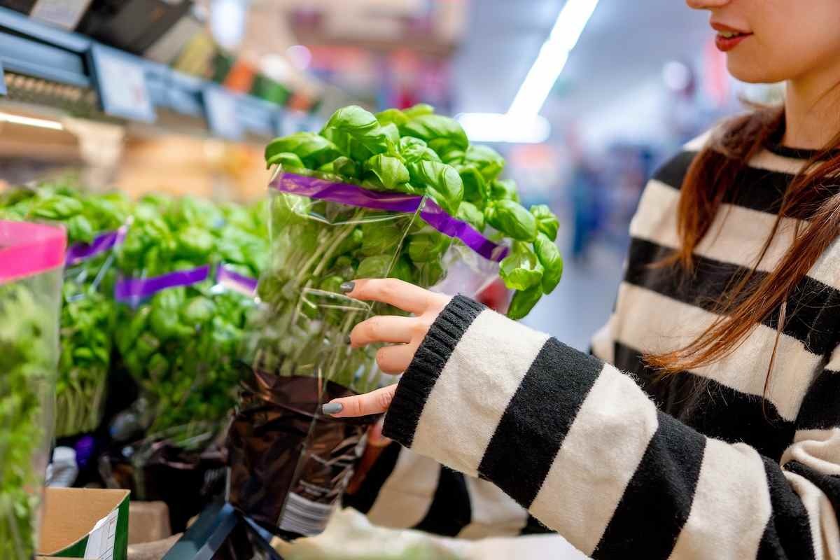 Primo piano di una donna tra piante di basilico al supermercato