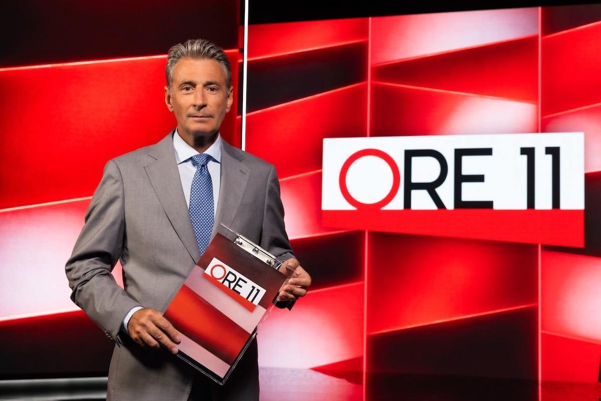 Milo Infante in giacca e cravatta conduce Ore 11
