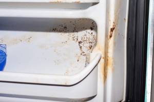 Frigorifero sporco con macchie e residui accumulati all’interno