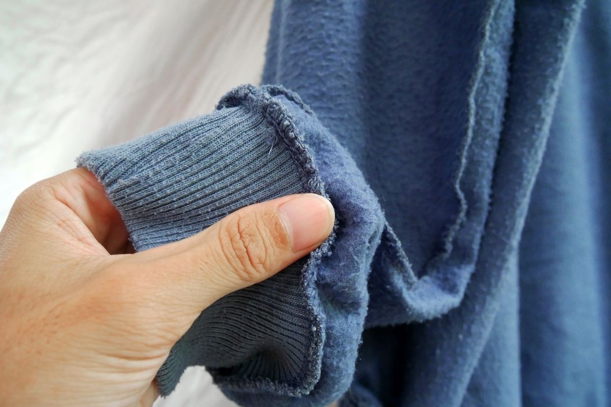 Mano che mostra il tessuto interno di una felpa blu