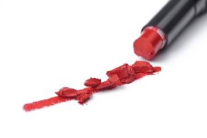 Rossetto rosso spezzato su una superficie bianca